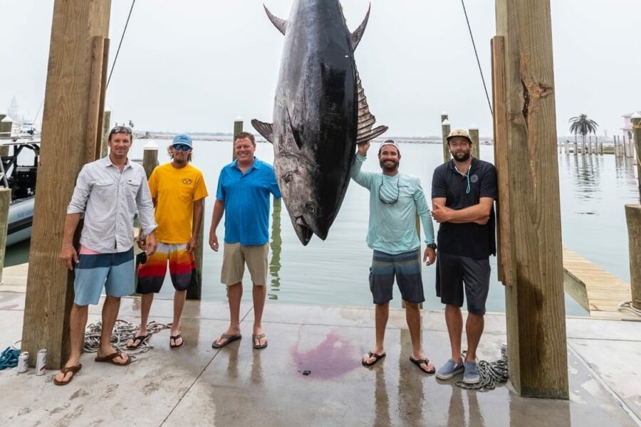 Group of anglers posing with a large yellowfin tuna catch at Port Aransas Fisherman’s Wharf.